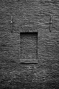A former Amsterdam warehouse in 2020, with a brick-up window and a tarred wall