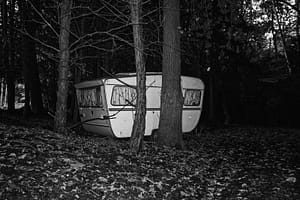 A caravan parked in the Amsterdam Forest, hidden underneath the trees