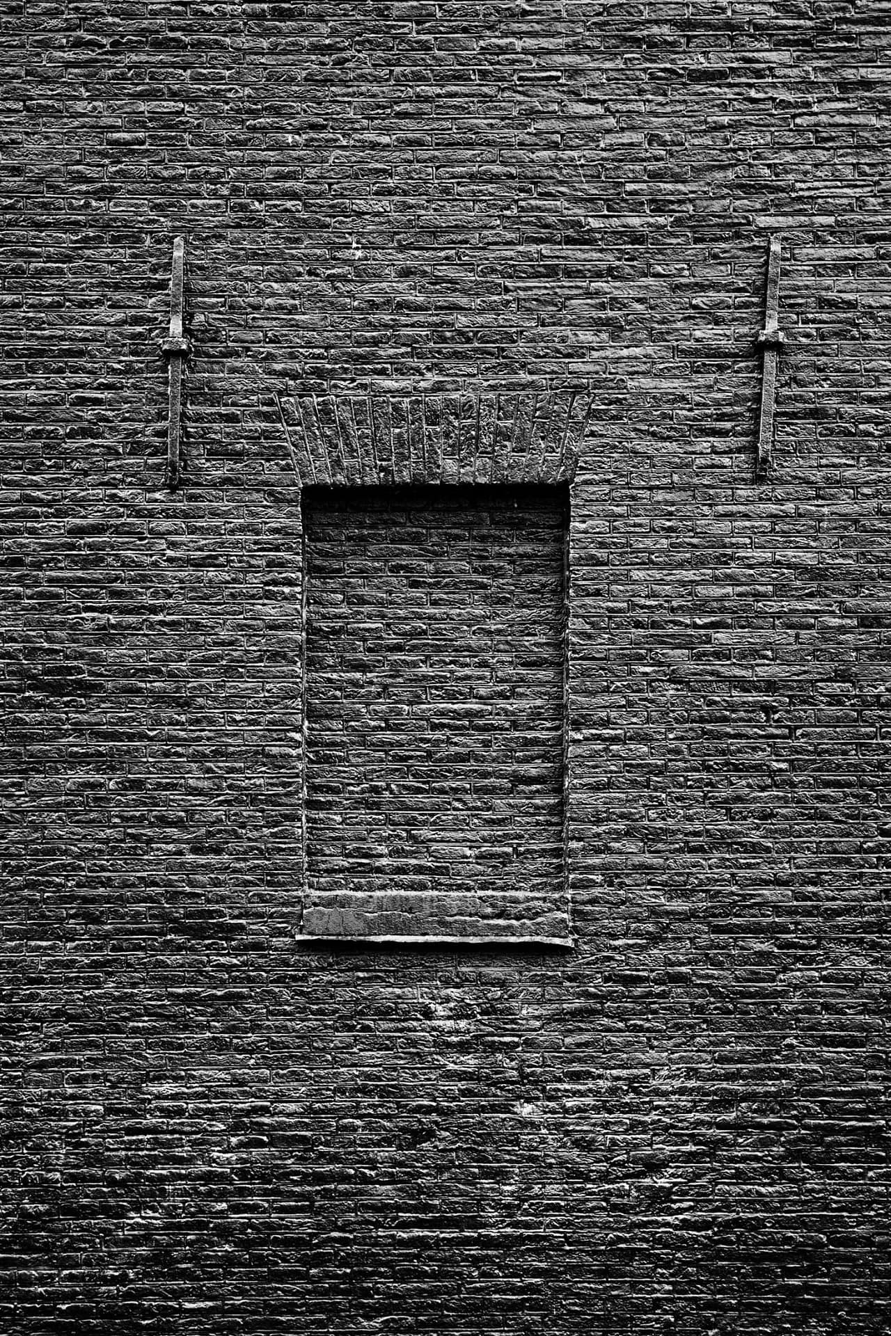 A former Amsterdam warehouse in 2020, with a brick-up window and a tarred wall