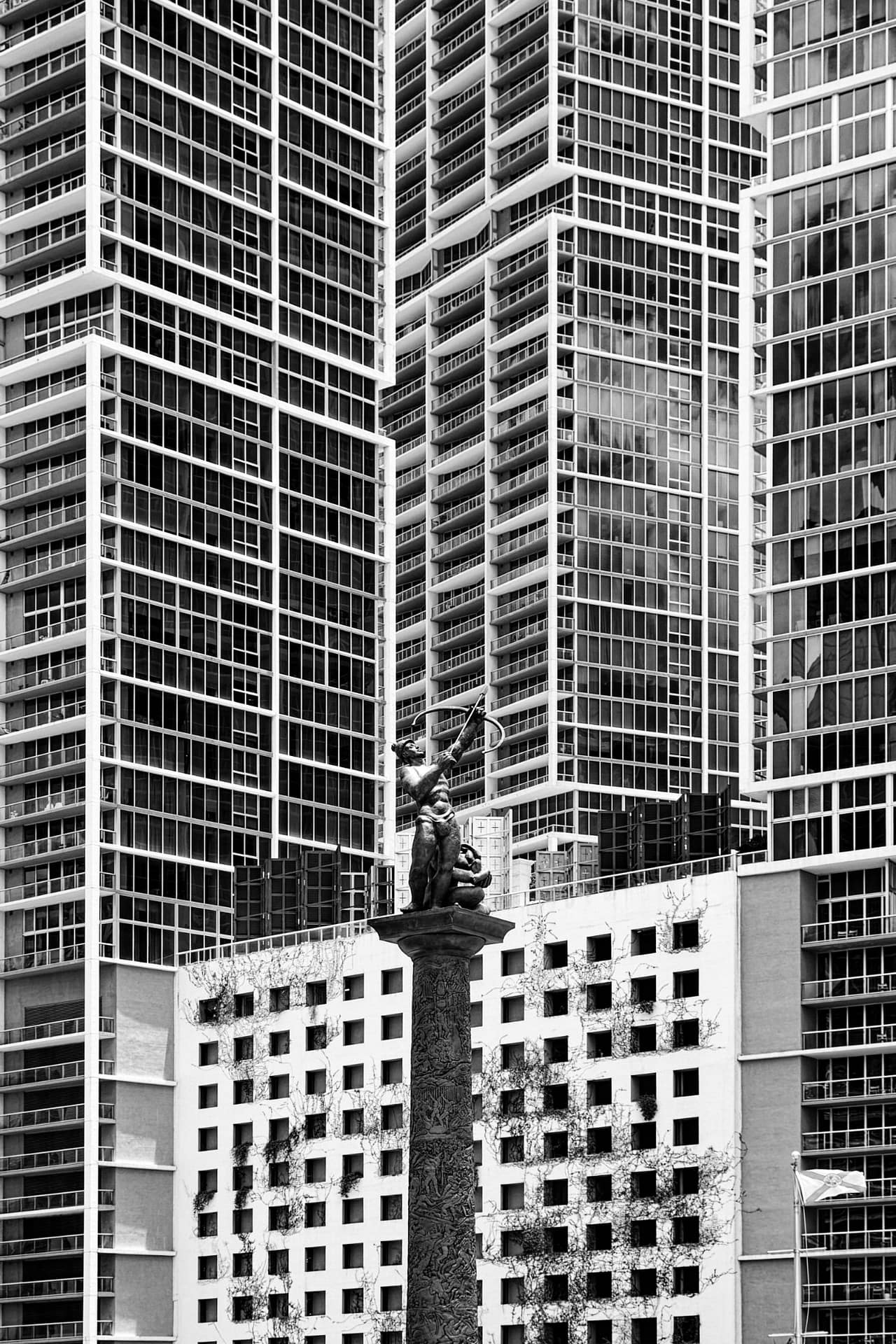 A photograph captures a Tequesta Indian warrior, his gaze fixed on the heavens, seeking a space in the vastness of eternity. His wife and child stand by his side, their presence a testament to the enduring bonds of family. The backdrop of towering buildings in Miami serves as a poignant reminder of the contrast between the warrior’s spiritual quest and the urban landscape of the modern world. This photograph was taken in 2016.
